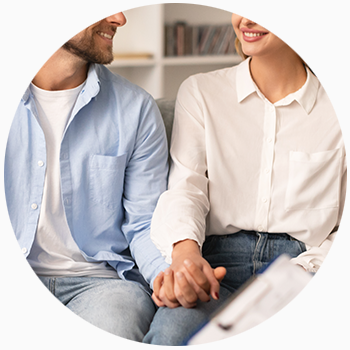 A couple looks at one another smiling, with hands held clasped together.