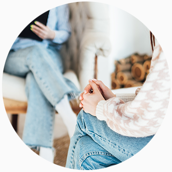 Picture of a person sitting with clasped hands while speaking with a counselor.